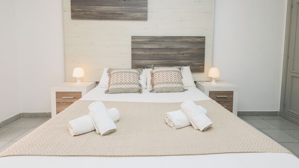A neatly arranged bedroom with a large bed, two bedside tables with lamps, and a herringbone-patterned rug. - Luxury Penthouse Sunny Terrace by Alma Homes (Los Cristianos)