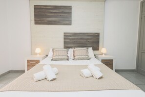 A neatly arranged bedroom with a large bed, two bedside tables with lamps, and a herringbone-patterned rug.