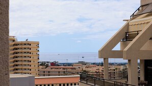 A coastal cityscape with buildings, a balcony, and a view of the sea. - Luxury Penthouse Sunny Terrace by Alma Homes (Los Cristianos)