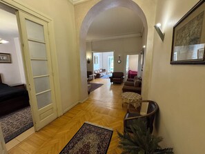 A hallway with a wooden floor leading to a living area with sofas and a coffee table. - Zamalek garden villa at the nile (Cairo Governorate)