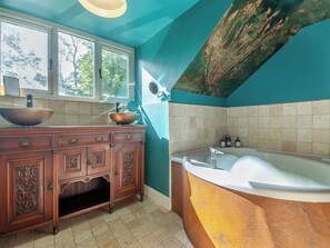 Une salle de bain avec un meuble-lavabo en bois, un grand lavabo et une baignoire.