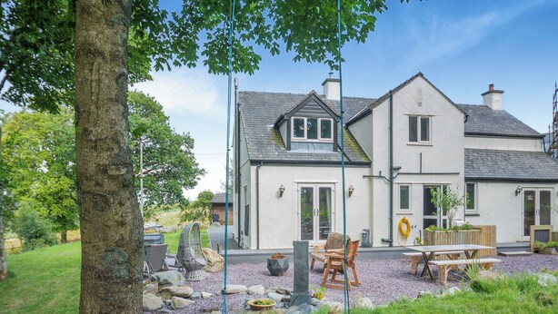 A house with a patio area, outdoor seating, and a swing. - 4 bedroom accommodation in Betws-Y-Coed (Betws-Y-Coed)