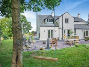 A house with a patio area, outdoor seating, and a swing. - 4 bedroom accommodation in Betws-Y-Coed (Betws-Y-Coed)