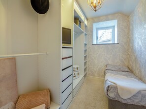 Un dressing avec des étagères blanches, un miroir et une fenêtre.