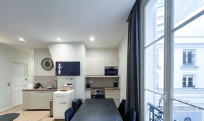 Un apartamento moderno con comedor, cocina y un amplio ventanal con vistas a la ciudad.