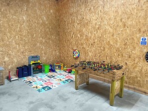 A room with a foosball table, a dartboard, and a colorful alphabet carpet.