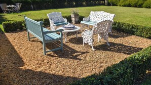 A garden patio with a table and four chairs, surrounded by gravel and greenery.