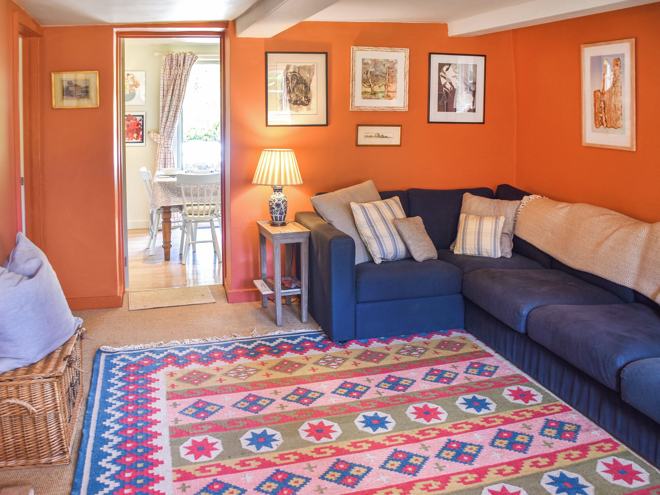 Een woonkamer met een blauwe bank, een kamerbreed tapijt en lijstwerken aan de muur.