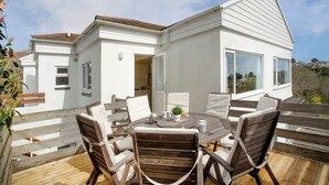 A white house with a large deck, a round wooden table, and four chairs. - 4 bedroom accommodation in St Mawes (St Mawes)