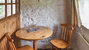 A wooden table with two chairs, a glass bowl, and a stack of books. - 1 bedroom accommodation in Camelford (Camelford)