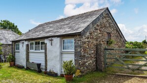 A stone cottage with a white exterior, a wooden door, and a small garden with potted plants. - 1 bedroom accommodation in Camelford (Camelford)