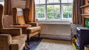 A cozy room with a large window, wooden furniture, and a radiator. - 1 bedroom accommodation in Camelford (Camelford)