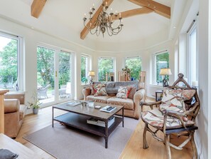 A spacious living room with a large window, a chandelier, and a wooden ceiling. - 3 bedroom accommodation in Strathcarron (Strathcarron)