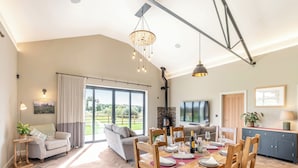 Un comedor espacioso con piso de espiga, una mesa grande dispuesta para seis personas y vistas al exterior a través de amplias ventanas.