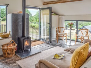 A cozy room with a fireplace, a sofa, a table with chairs, and a view of greenery outside.