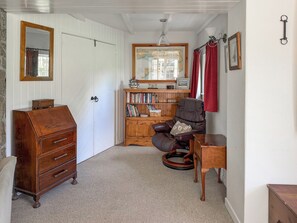 A room with a wooden dresser, a leather chair, a bookshelf, and a map on the wall. - 4 bedroom accommodation in St Blazey (Par)