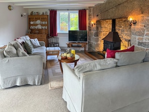 Un salón acogedor con chimenea de piedra, televisor y un mueble de madera con vajilla.