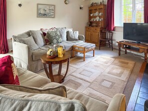 A living room with a sofa, coffee table, wooden cabinet, and a television.