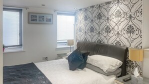 A bedroom with a bed, bedside tables, a lamp, and a window with blinds.