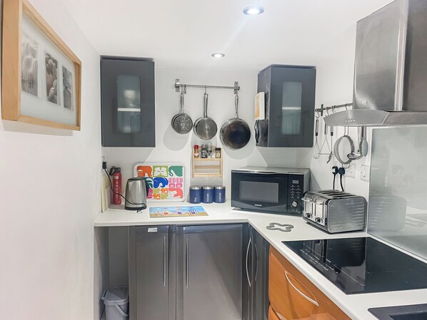 Una cocina compacta con microondas, tostadora y armarios de acero inoxidable.
