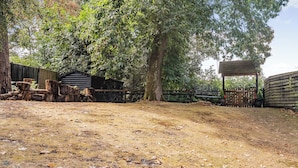 A rustic outdoor area with a wooden bench, a fenced garden, and a building with a sloped roof. - The Retreat - UK50421 (Ringwood, New Forest)