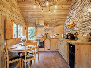 Ein Holzblockhaus im Inneren mit Essbereich, Küche und einer Steinwand.