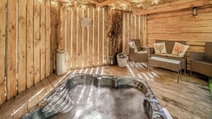 A wooden cabin interior with a hot tub, wicker furniture, and string lights. - The Retreat - UK50421 (Ringwood, New Forest)