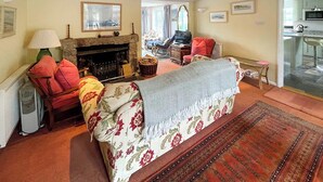 Una sala de estar acogedora con chimenea, un sofá y un televisor.