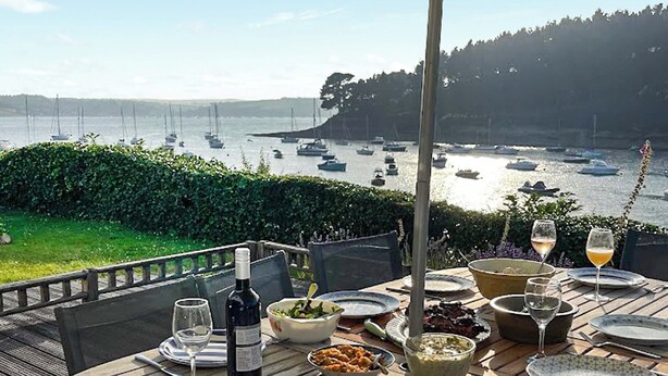 Zona de comedor al aire libre con una mesa lista para comer, con vistas a un puerto deportivo lleno de barcos.