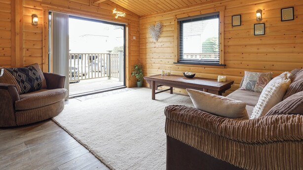 A cozy wooden cabin interior with a sofa, a table, and a potted plant.