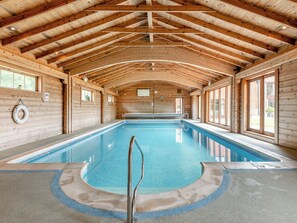 An indoor swimming pool with wooden beams and large windows.