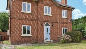 A two-story brick house with a white door, multiple windows, and a satellite dish. - 3 bedroom accommodation in Eakring (Eakring)