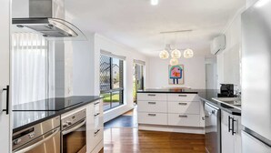 Une cuisine moderne dotée d’appareils électroménagers en acier inoxydable, de meubles blancs et offrant une vue sur l’extérieur.