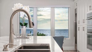 A modern kitchen with a large window offering a view of the sea. - Beachfront + Pool/Spa + Elevator + PingPong Table (Indian Rocks Beach)