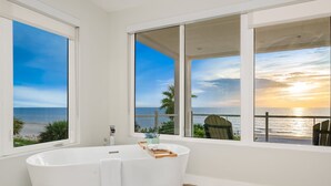 A modern bathroom with a freestanding bathtub, large windows, and a view of the ocean. - Beachfront + Pool/Spa + Elevator + PingPong Table (Indian Rocks Beach)