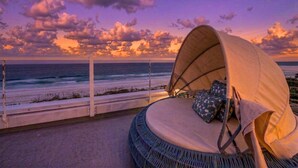 A beachside cabana with a cushioned seating area, a view of the ocean, and a railing. - Beachfront + Pool/Spa + Elevator + PingPong Table (Indian Rocks Beach)