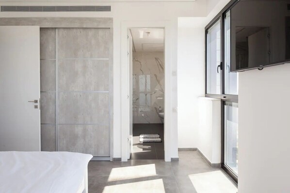 A modern hotel room with a large bed, a walk-in closet, and a bathroom with a marble backsplash. - Prestigious penthouse in a luxury tower (Bat Yam)
