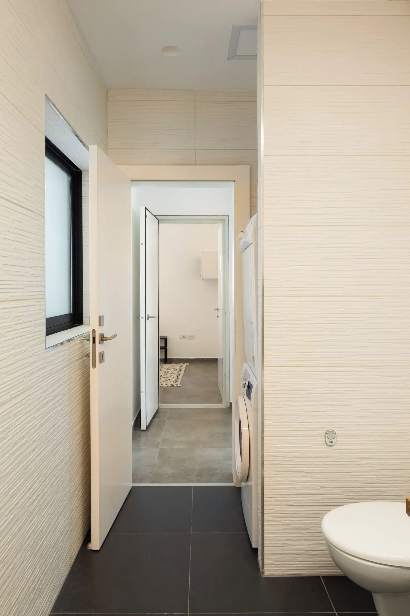 Ein modernes Badezimmer mit Toilette, Waschmaschine und Fenster.