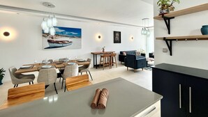 Ein modernes Wohnzimmer mit Essbereich, mit einem großen Gemälde, einer Couch, einem Couchtisch und einem Fernseher.