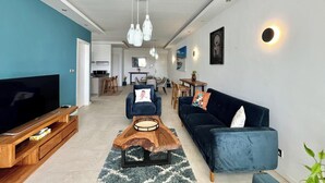 Ein modernes Wohnzimmer mit Fernseher, Sofa, Couchtisch und Essbereich.