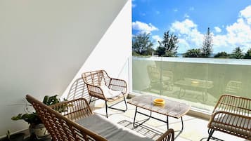 A balcony with wicker furniture, a table, and a potted plant.