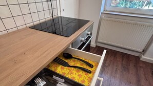 A kitchen with a wooden countertop, a black induction cooktop, and a drawer with utensils. - Spacious Central 3Bedroom flat for 8 guests (Zeitz)
