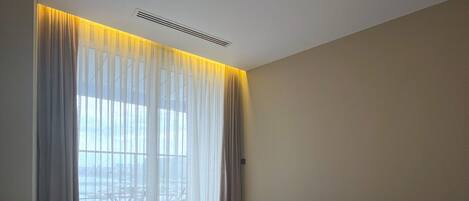 A hotel room with a large bed, a ceiling light, and a window with curtains.