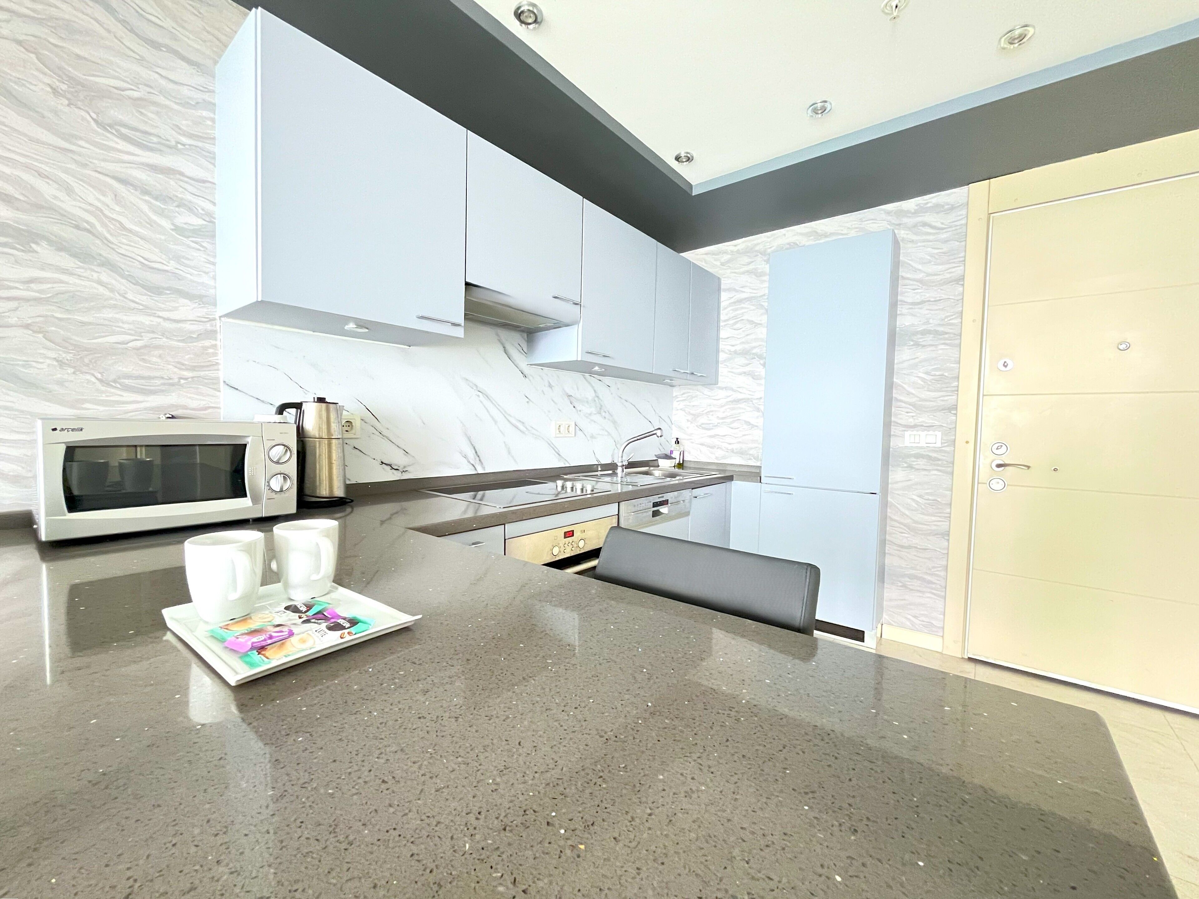 A modern kitchen with a microwave, sink, and a bench.
