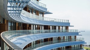A modern multi-story building with curved balconies and large windows, overlooking a body of water. - Flex Ottomare Suites (İstanbul)