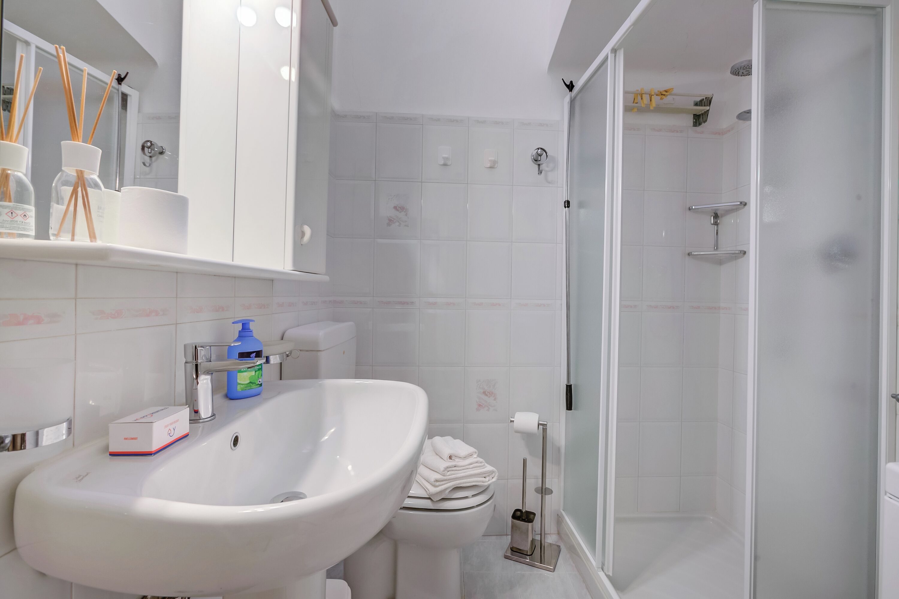 A bathroom with a white sink, toilet, and shower.