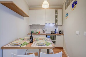 Een moderne keuken met witte kastjes, een houten aanrechtblad en een eethoek voor vier personen.