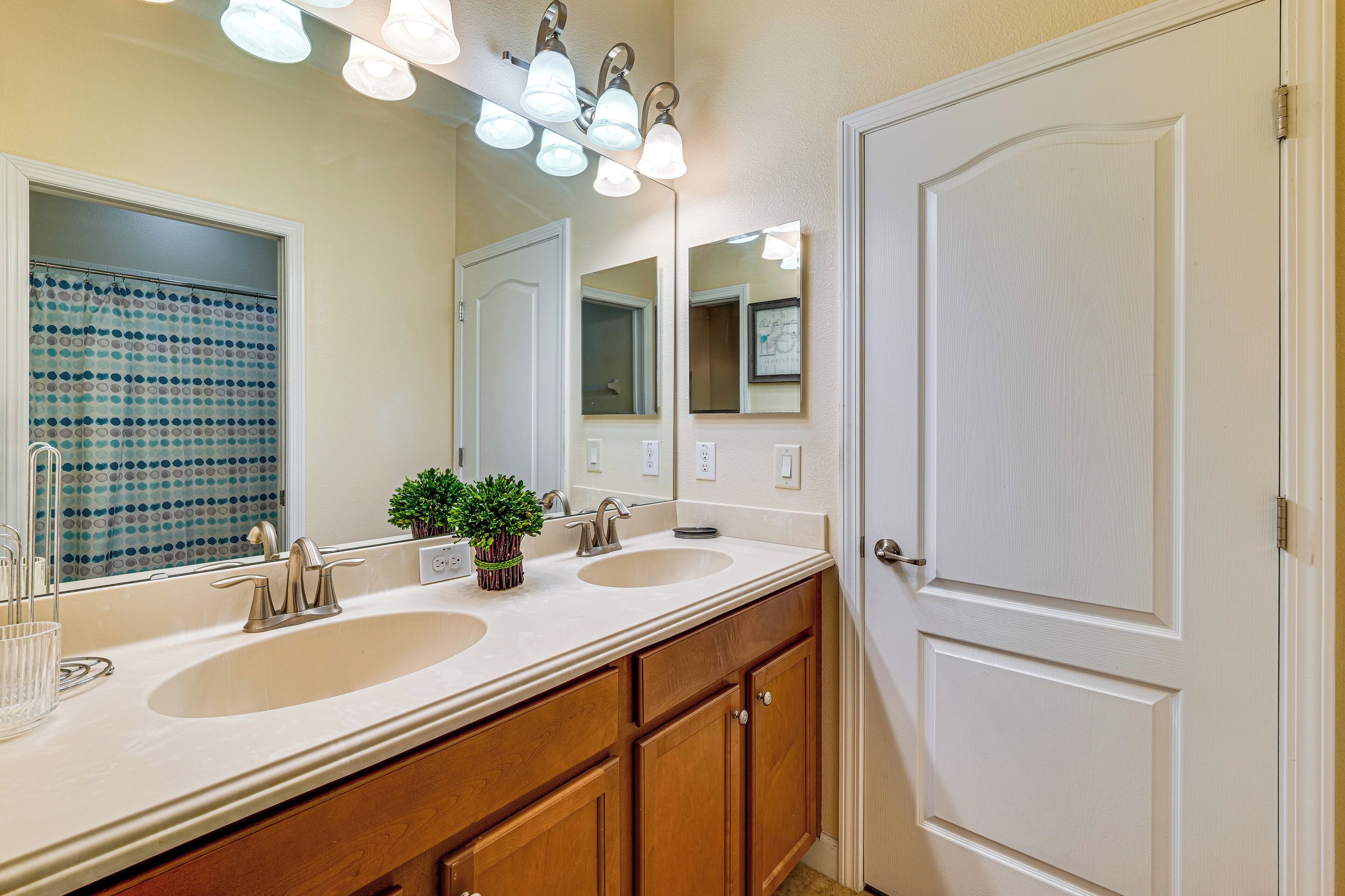 A bathroom with two sinks, a large mirror, and a door.