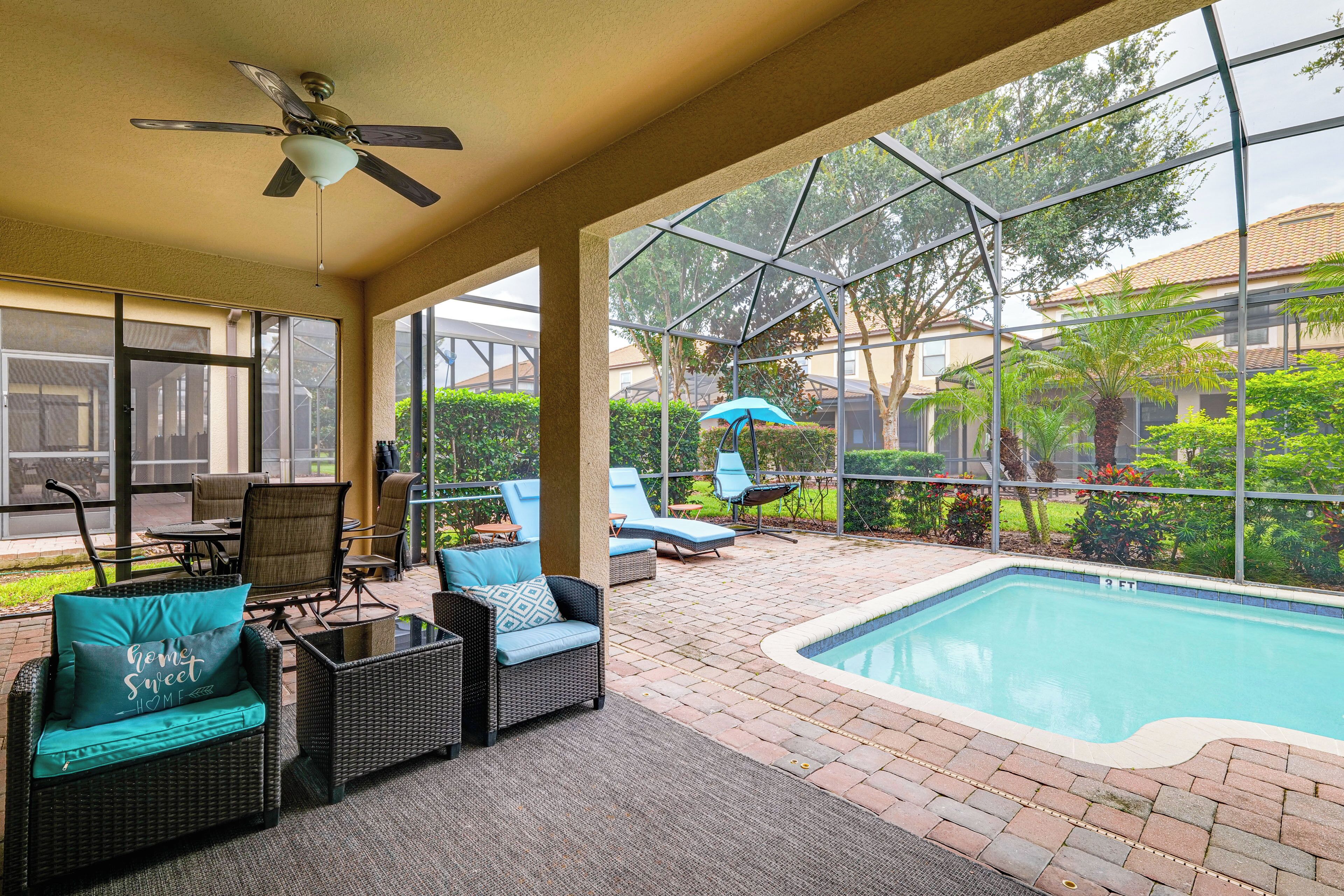 A covered outdoor area with a pool, lounge chairs, and a ceiling fan.