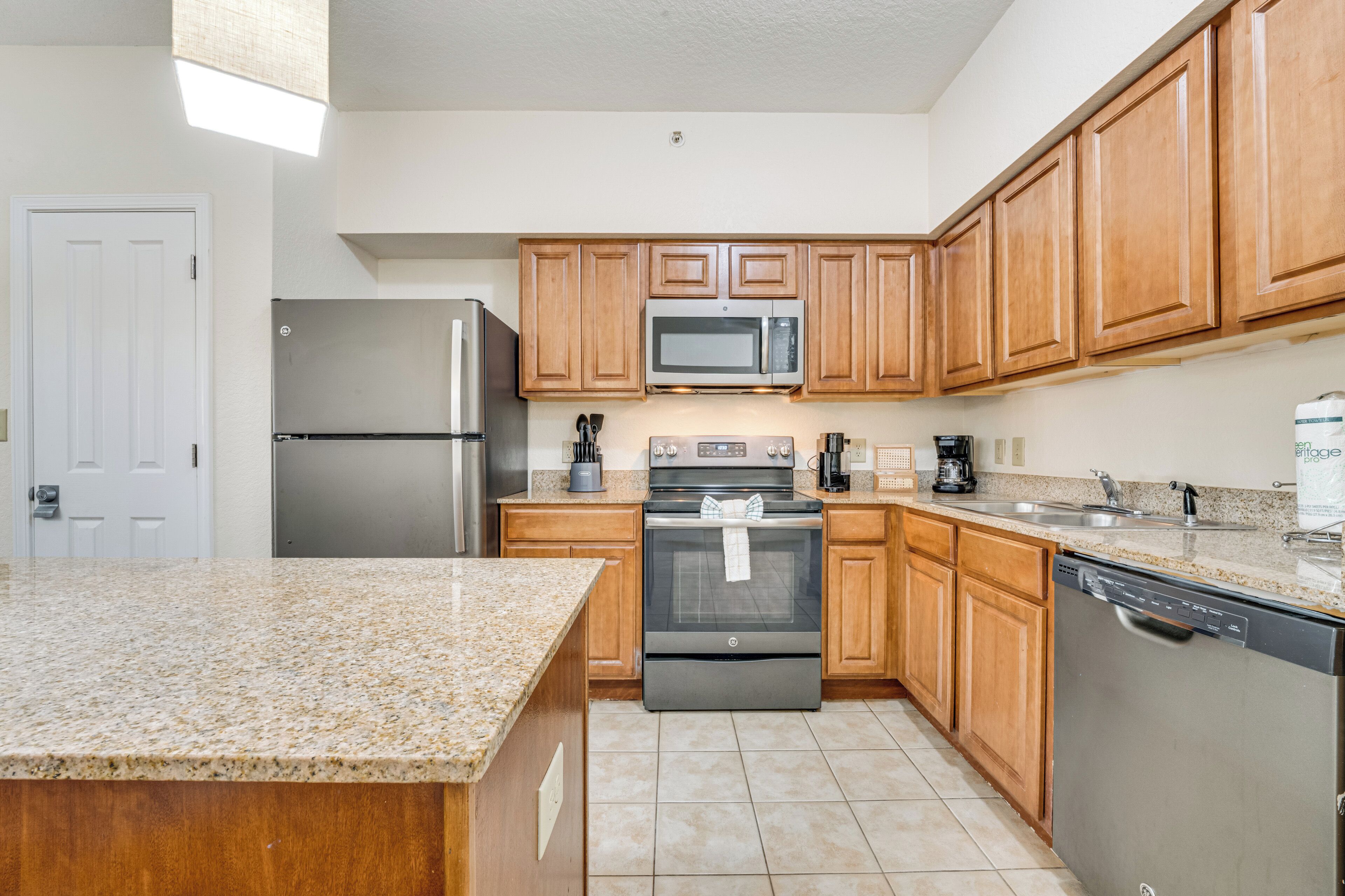 A kitchen with wooden cabinets, a stainless steel refrigerator, a microwave, an oven, and a dishwasher.